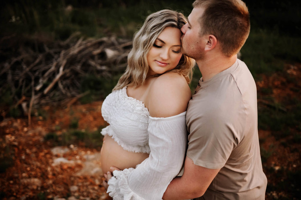 maternity photographer in Springfield Mo captures pregnant couple kissing on trail
