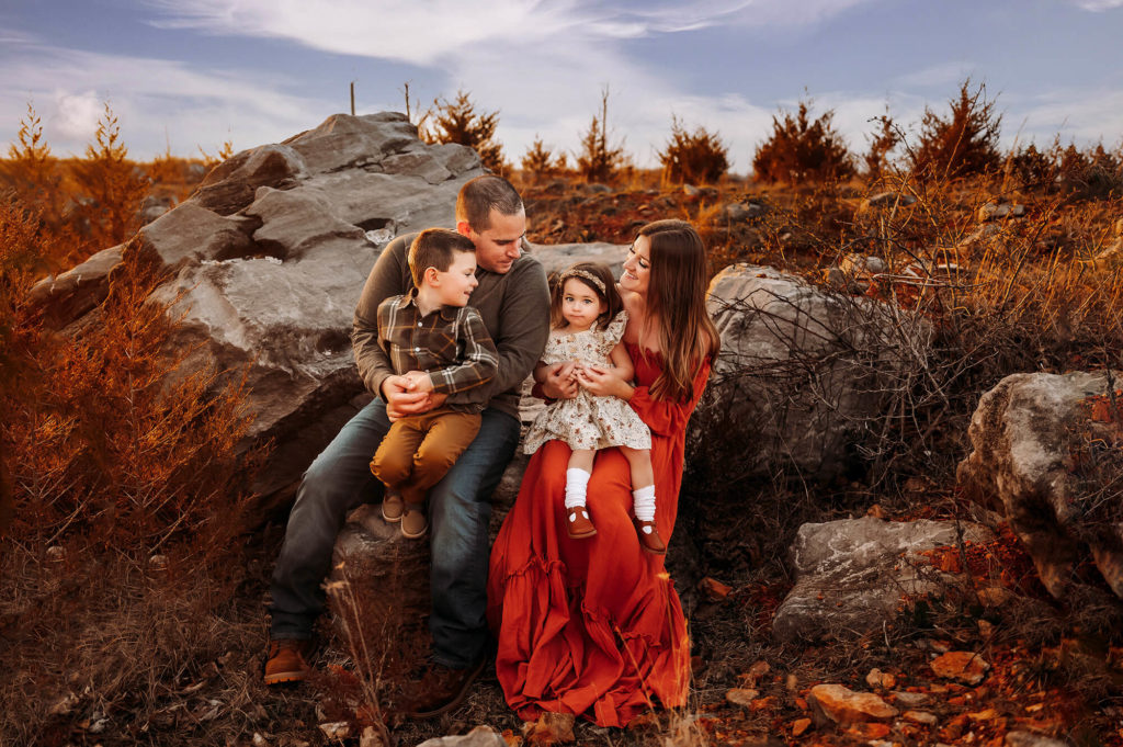 Springfield MO family photographer captures family sitting on rock at sunset