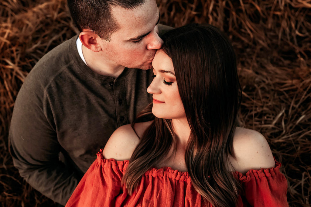 professional photography in Springfield MO captures couple cuddling in field at sunset