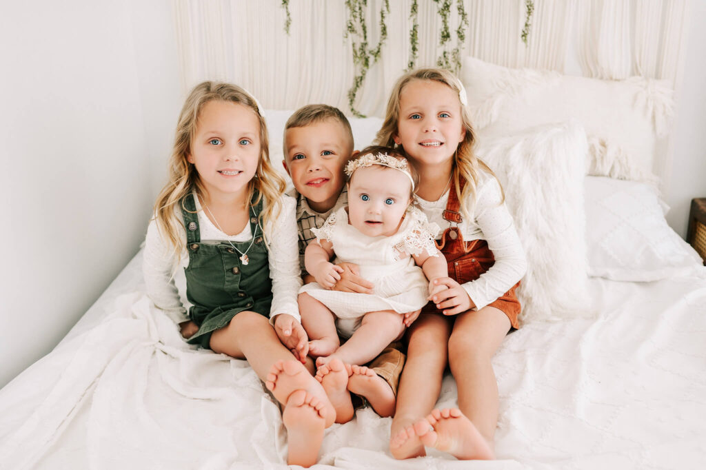 kids cuddling on bed smiling captured by Springfield MO family photographer The XO Photography