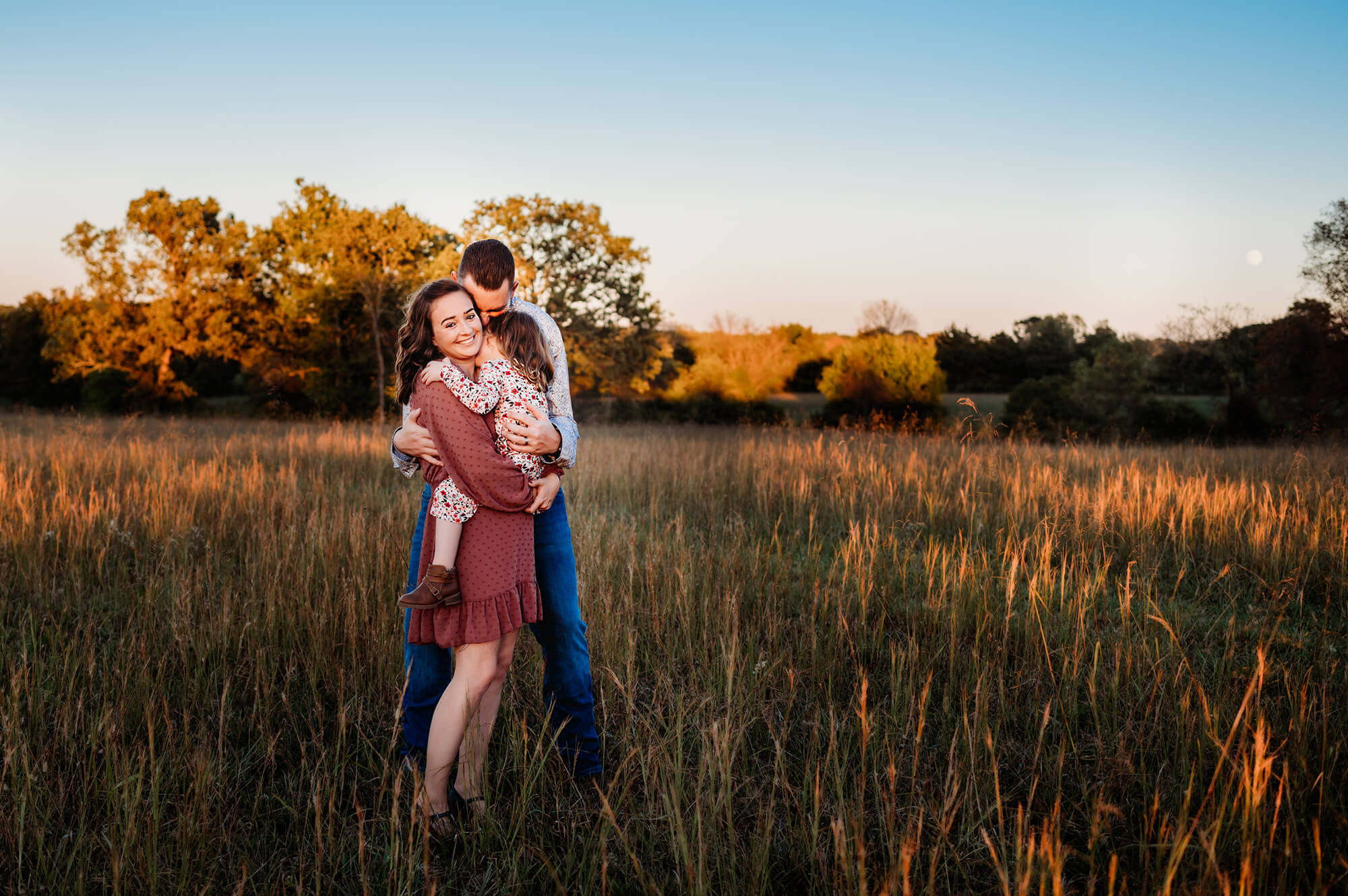 photographer in Kansas City captures family cuddling in field at sunet