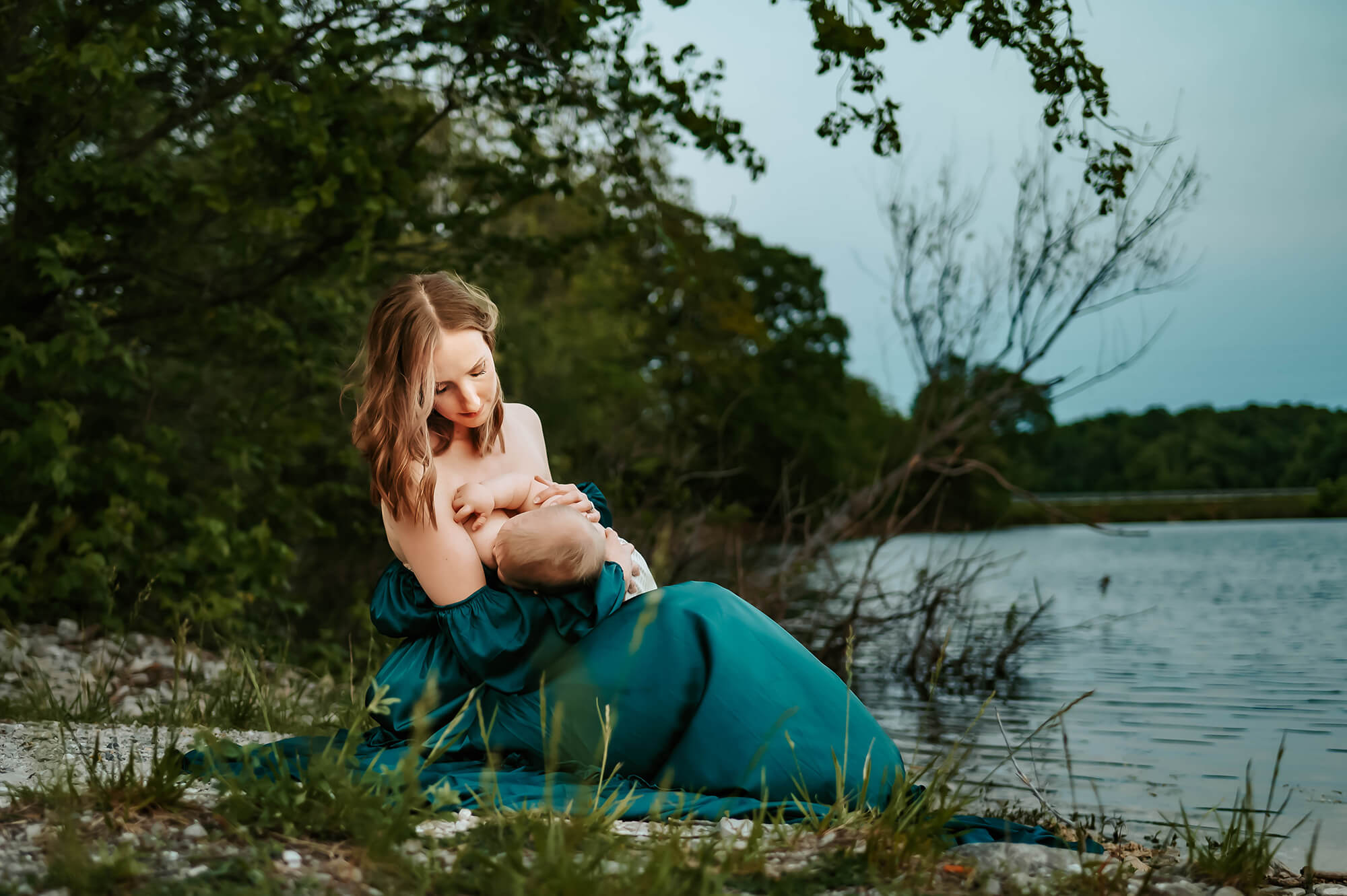 mom breastfeeding baby near lake during lactation consultant in Kansas City captured by kansas city photographer The XO Photography