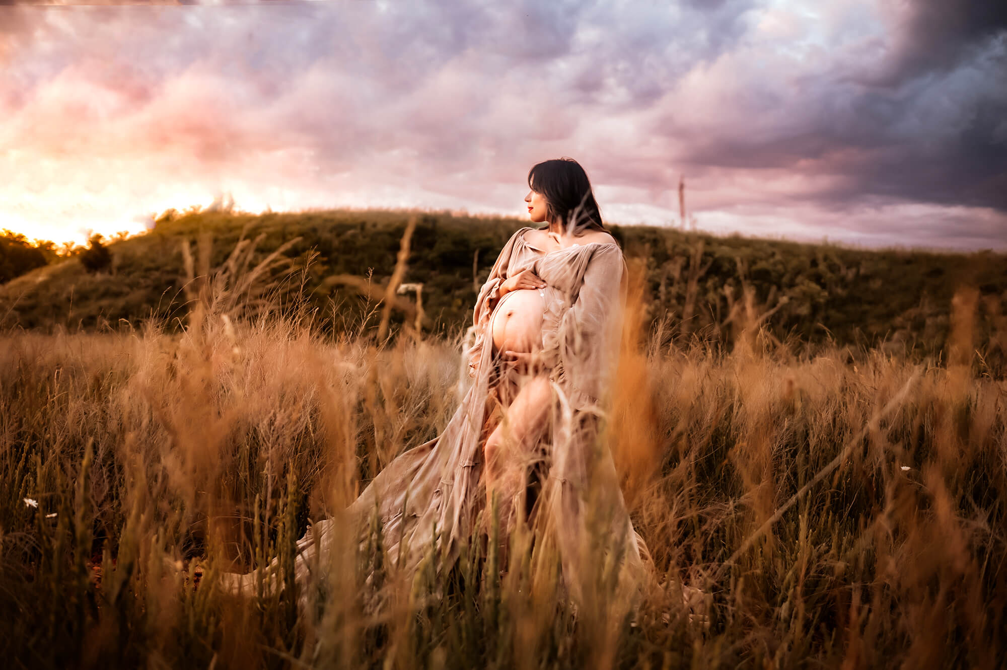 lifestyle photographer in kansas city captures pregnant mom standing in a field at sunset