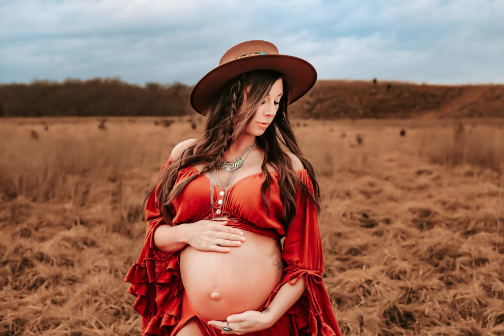 maternity photographer in Springfield MO Jessica Kennedy of The XO Photography captures pregnant mom hugging belly in field at sunset