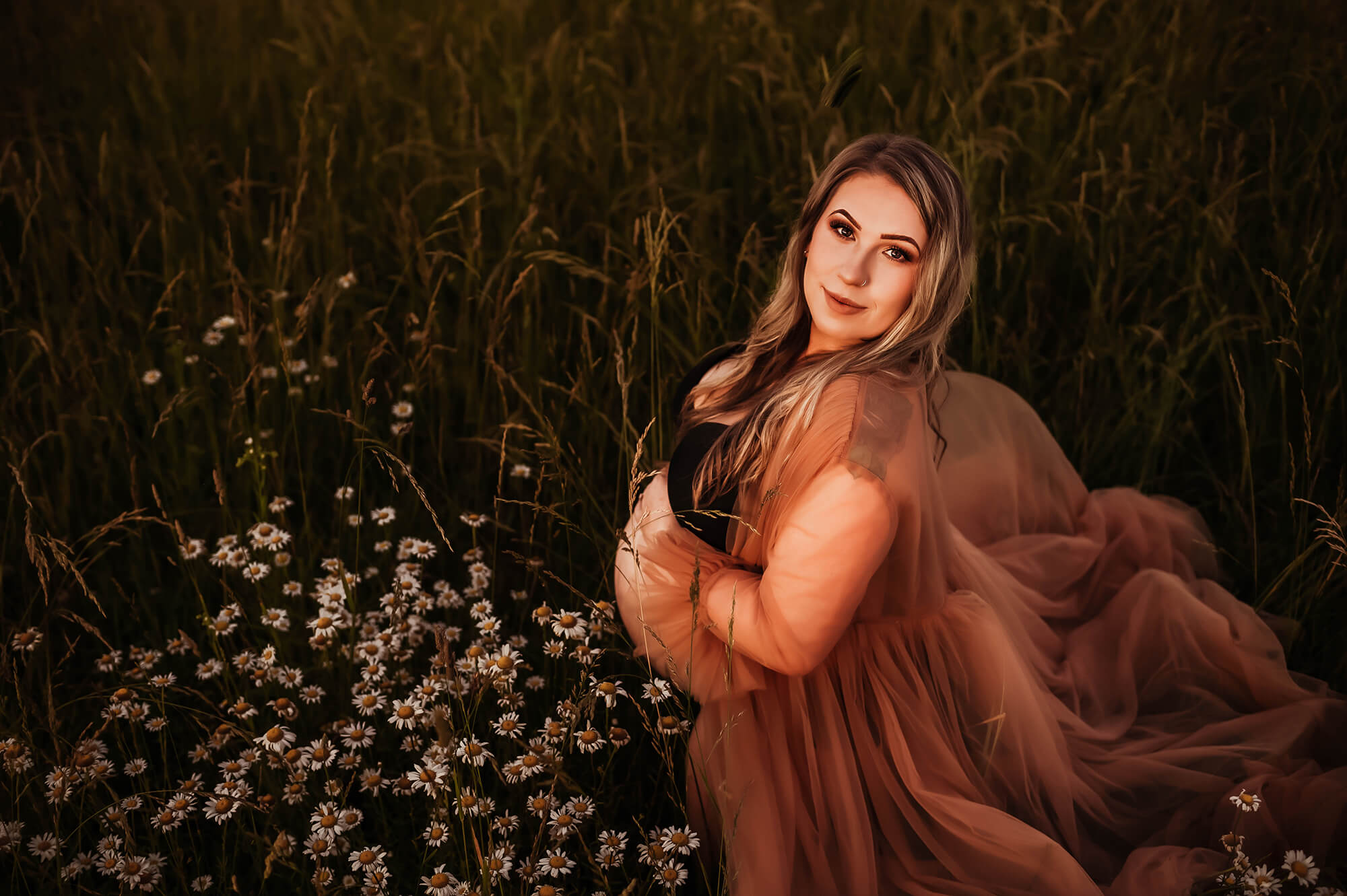 Springfield MO maternity photographer captures pregnant mom kneeling in flower field after mercy obgyn in Springfield MO