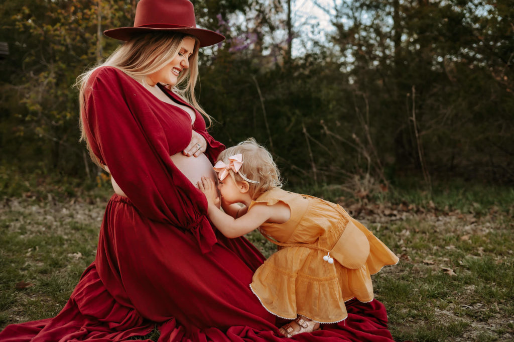 Springfield MO photographer captures pregnant mom holding belly with toddler kissing belly