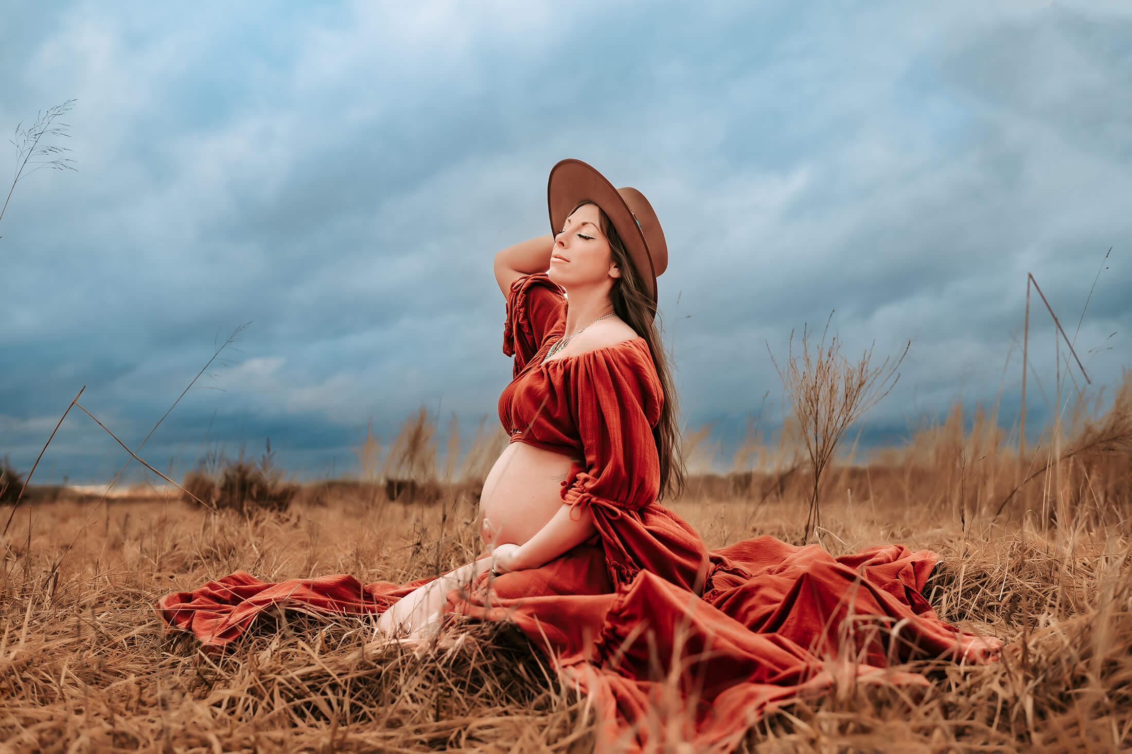 Springfield MO maternity photographer captures pregnant mom kneeling in field as storm rolls in