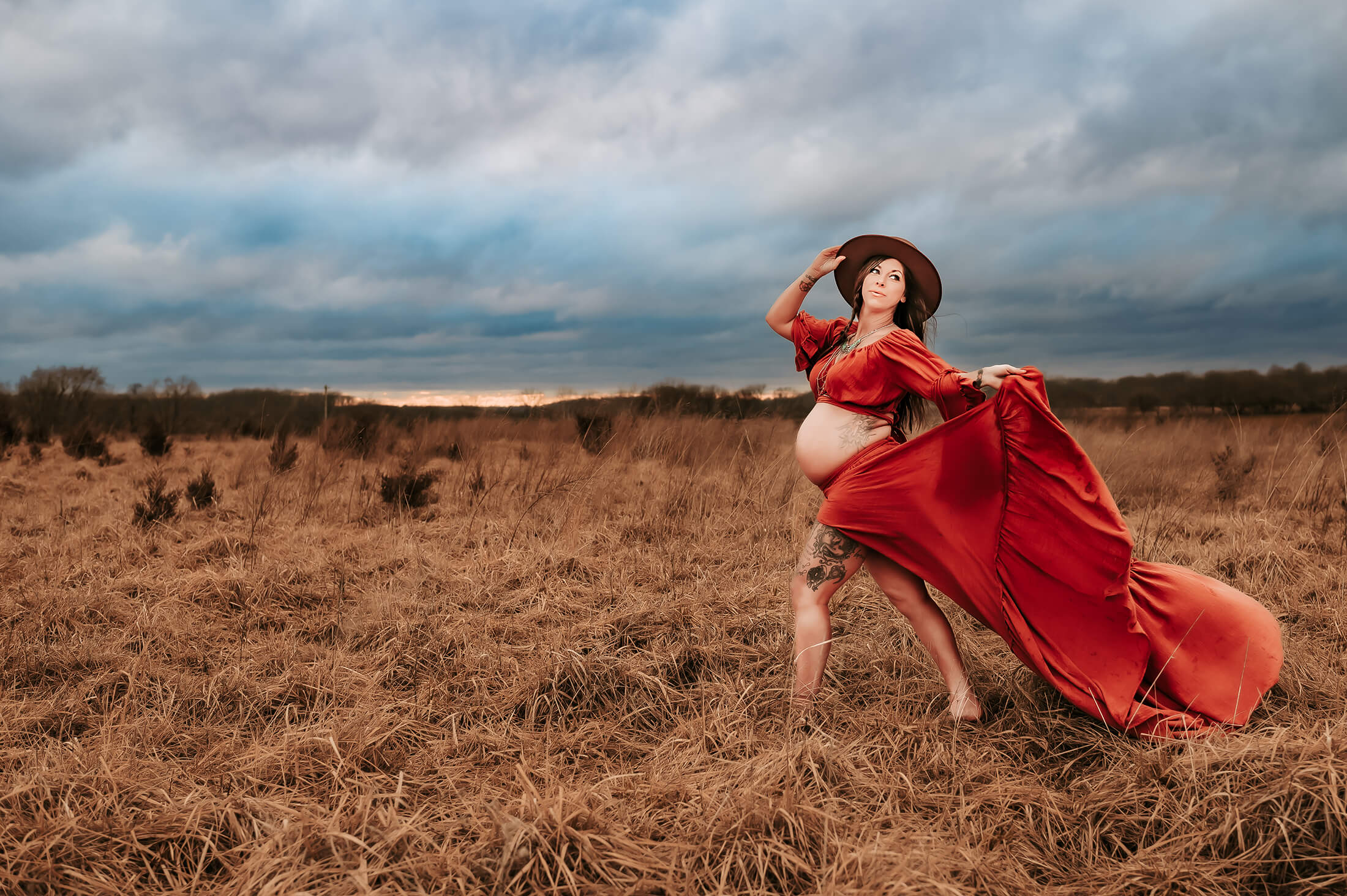 maternity photographer in kansas City captures pregnant mom walking in field with red dress