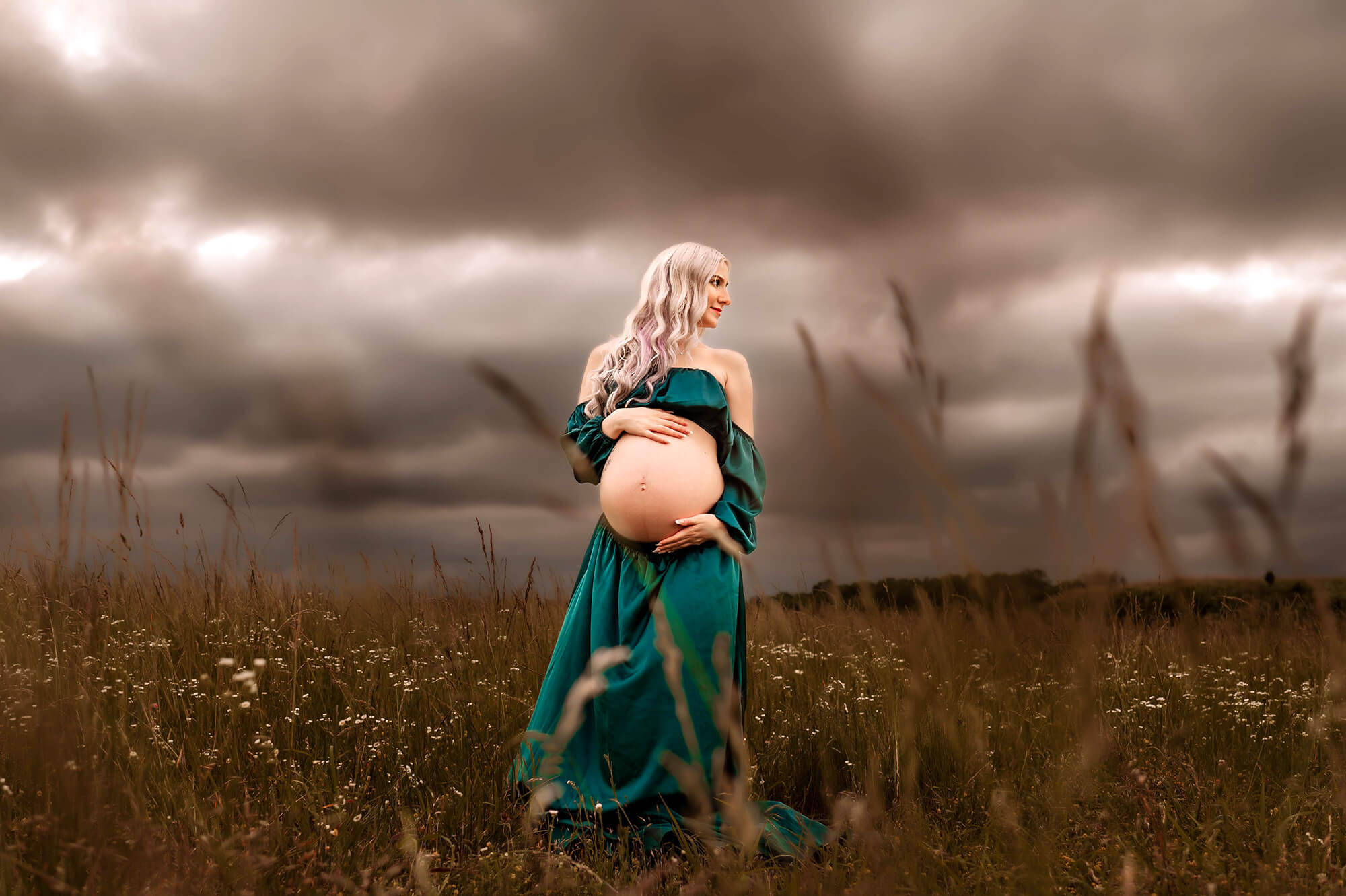 Springfield MO maternity photographer captures pregnant mom standing in field with storm rolling in