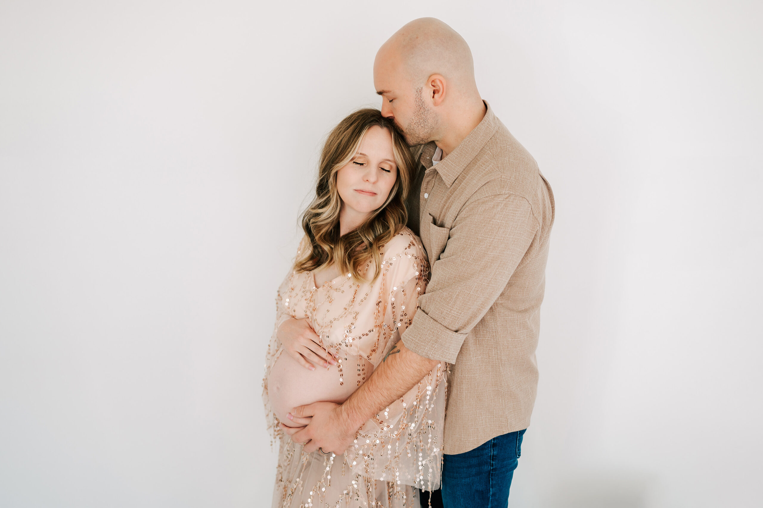 husband kissing pregnant mom forehead in Springfield MO maternity photography studio