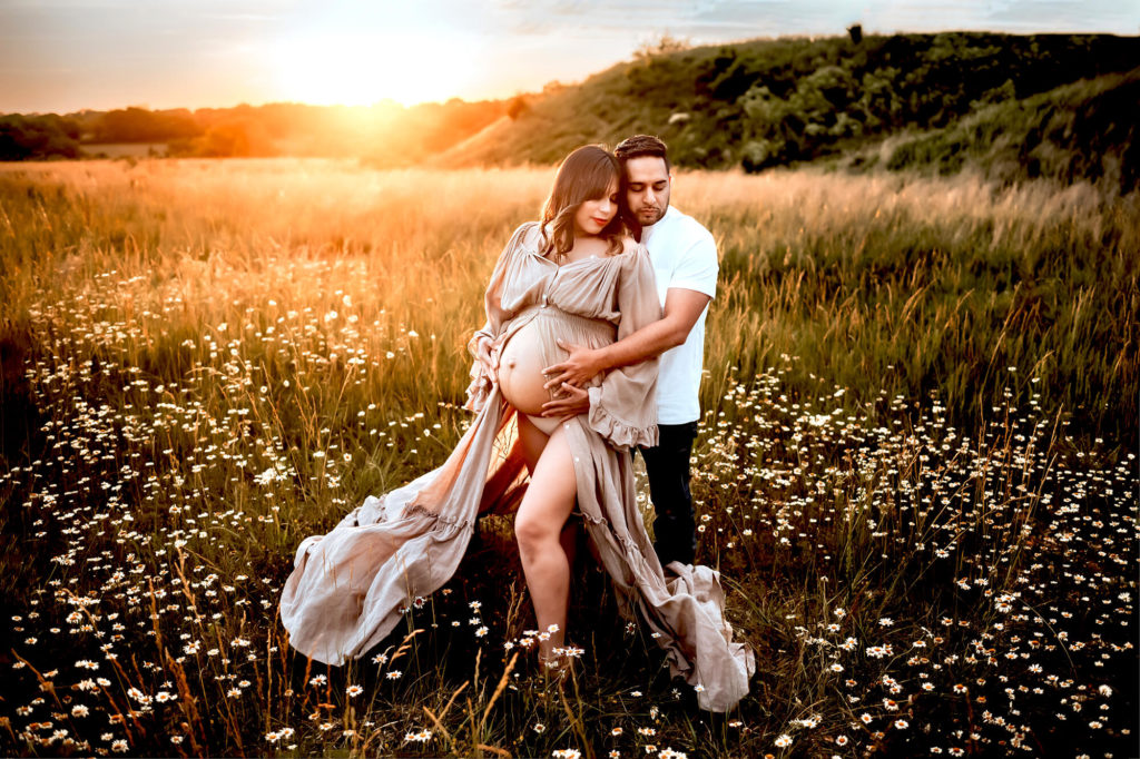 photographer in Overland Park captures couple hugging in field of daisies at sunset