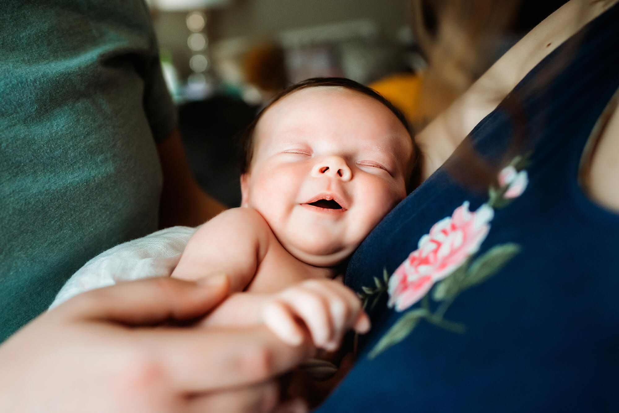 Overland Park newborn photographer captures baby smiling in parents arms as they baby sleeps