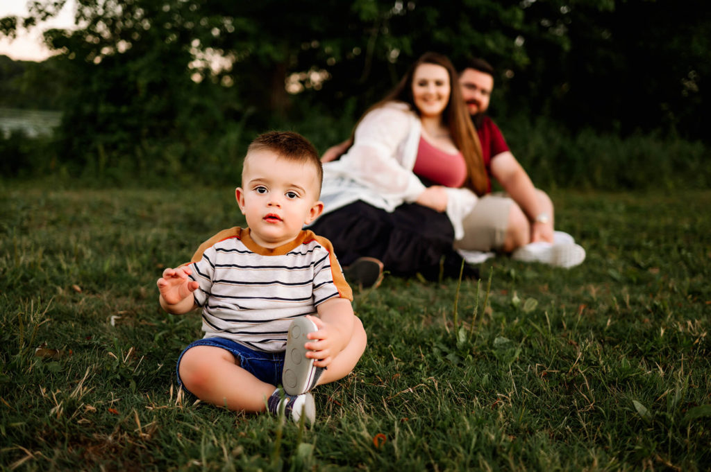 lifestyle photo in Kansas City of baby boy sitting in grass with parents 