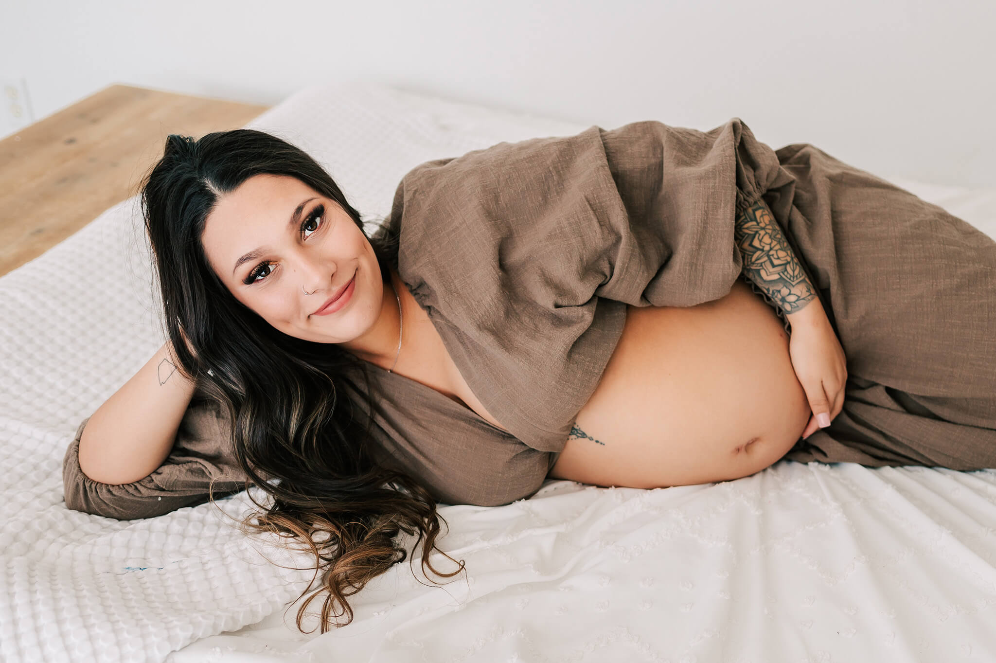 pregnant mom laying in bed in Springfield MO maternity photography studio