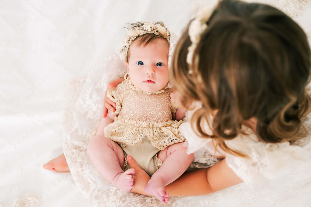 Kansas city newborn photographer captures sister holding baby sister with outfits from baby stores in Kansas City
