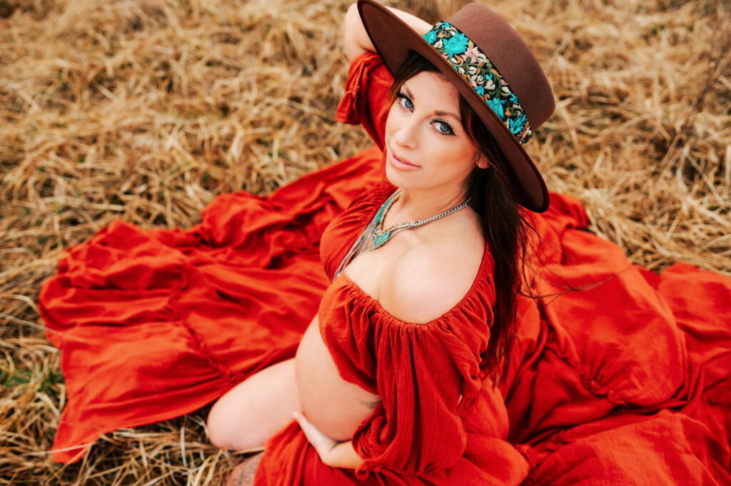 Maternity photographer in kansas city captures mom in red dress and hat from maternity stores in Kansas City
