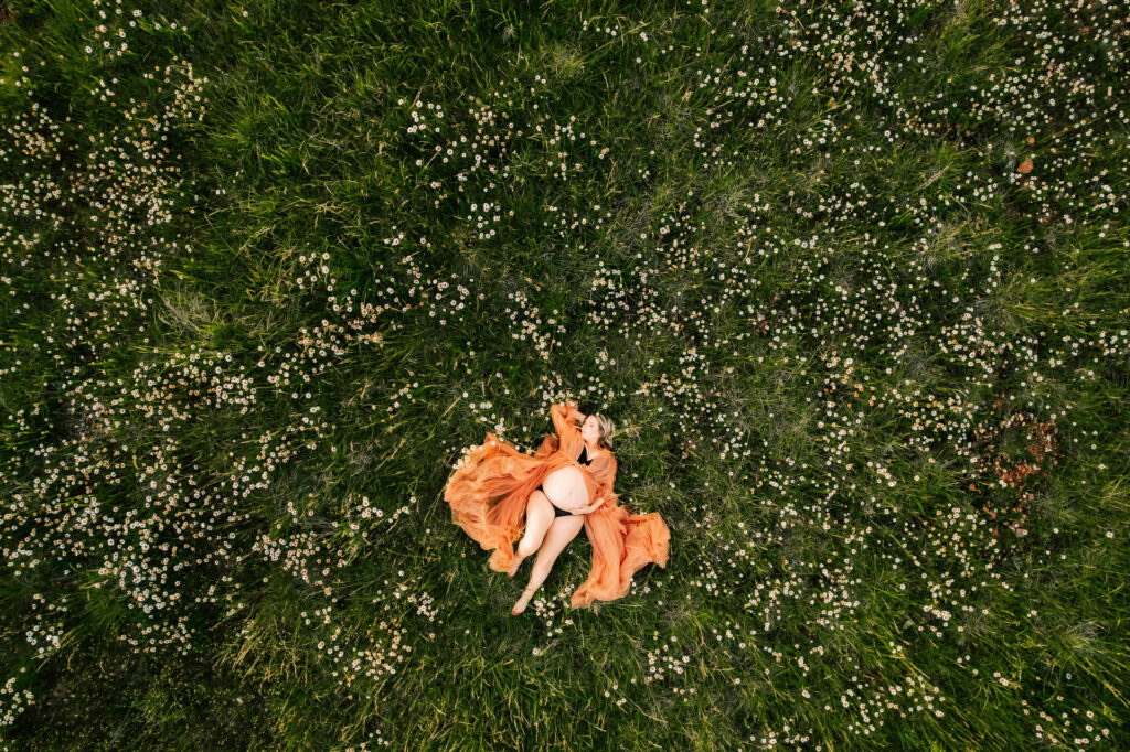 pregnant mom laying in field of flowers captured by Kansas city maternity photographer