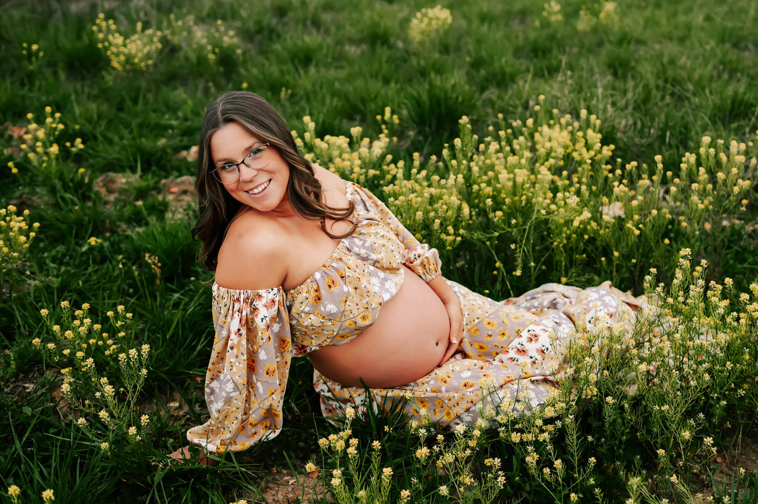 mom in floral dress smiling during outdoor Springfield MO maternity photography session