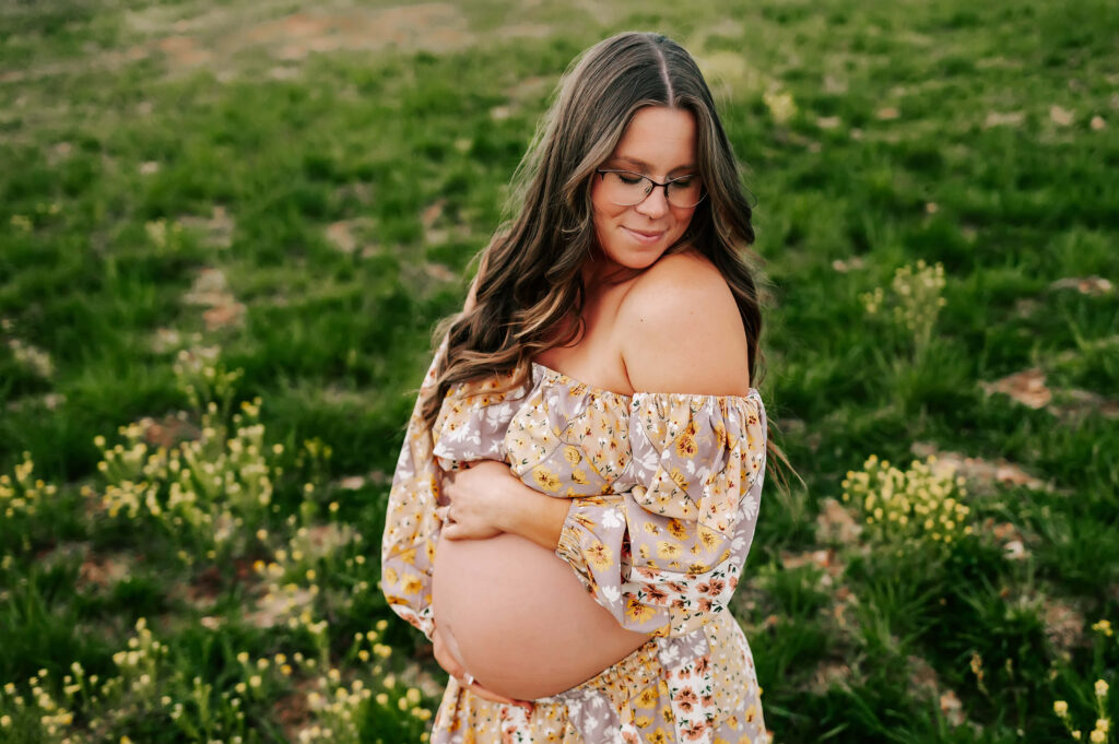 maternity photo in Springfield MO of pregnant mom in floral dress in field