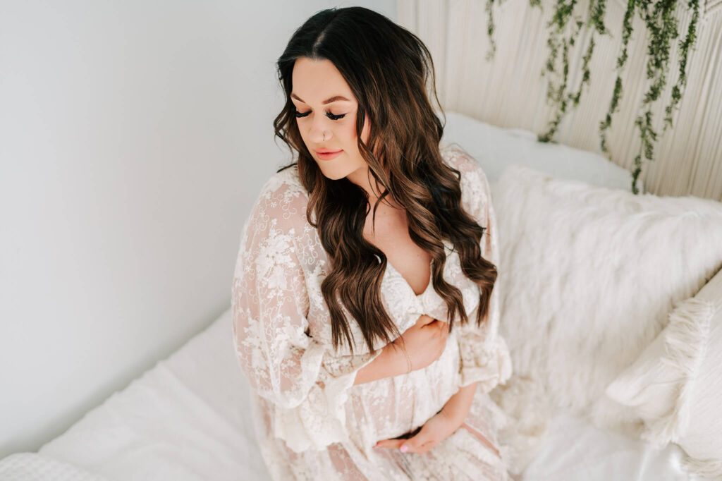 Kansas city maternity photographer captures mom hugging bump in lace dress from maternity store in Kansas City