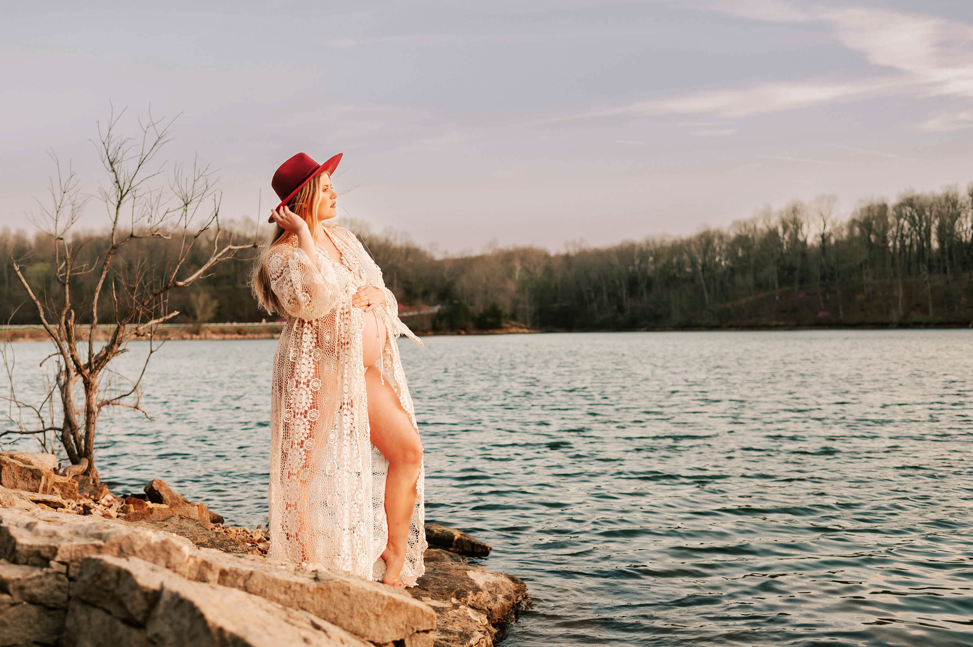 Kansas City maternity photographer captures pregnant couple kissing on rock in the fall leaves