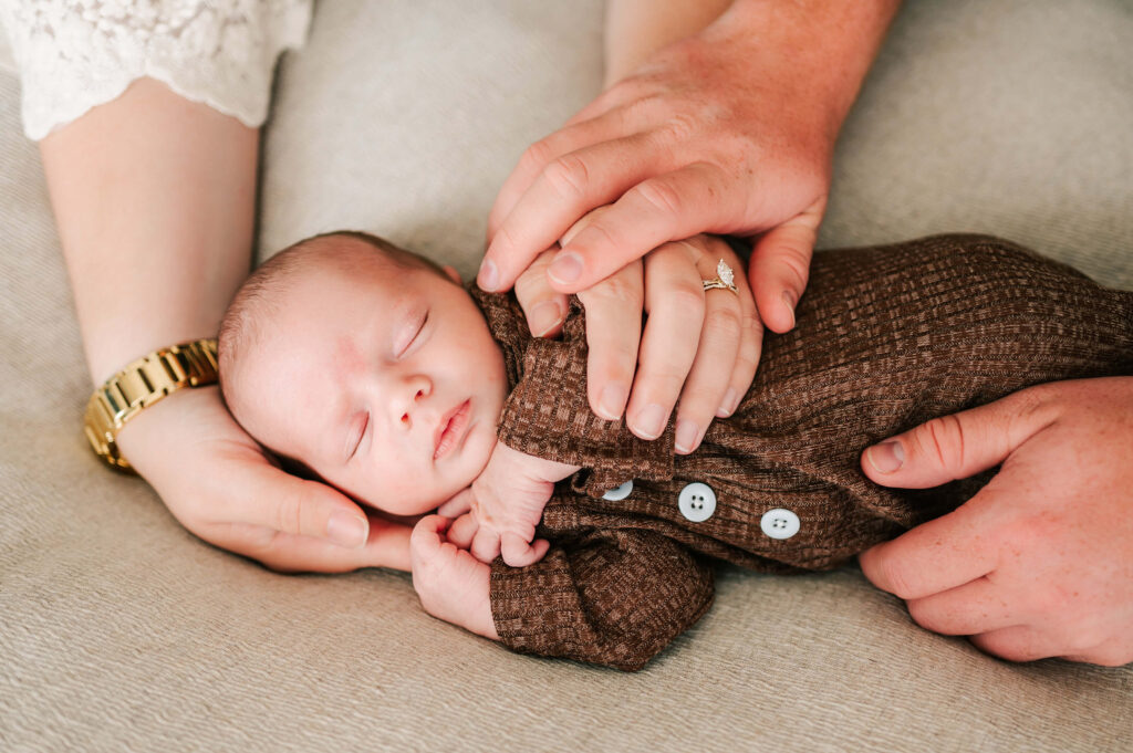 sleeping baby in parents hand captured by Overland Park newborn photographer