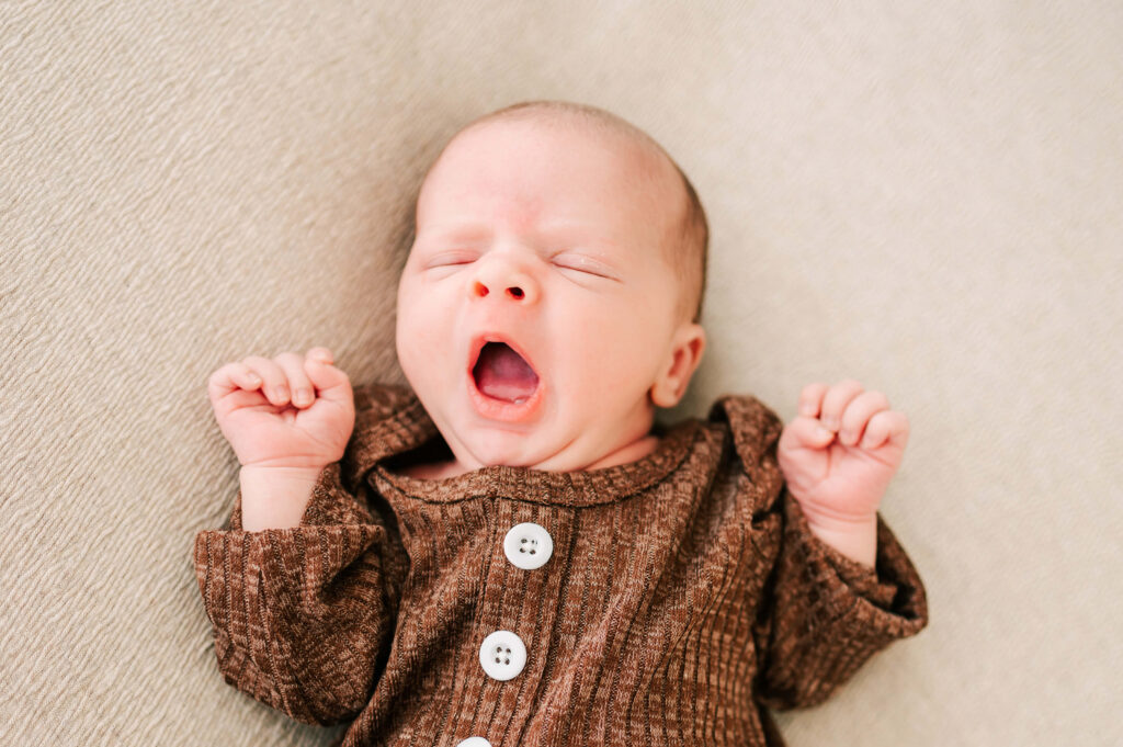 Kansas City newborn photographer captures yawning baby in nightgown from baby store in Kansas City