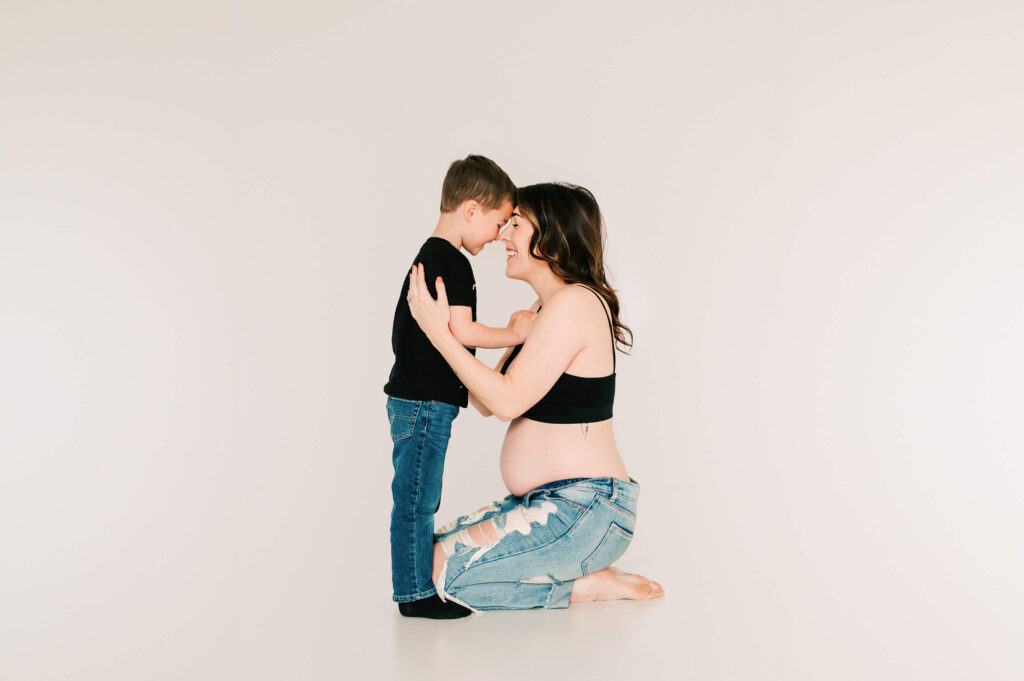 pregnant mom going nose to nose with toddler boy as they prepare for a new baby