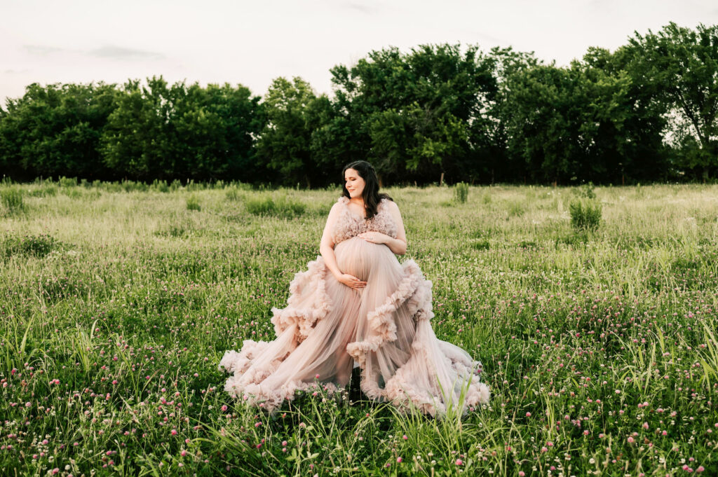 pregnant mom holding baby bump in open field captured by Branson maternity photographer The XO Photography