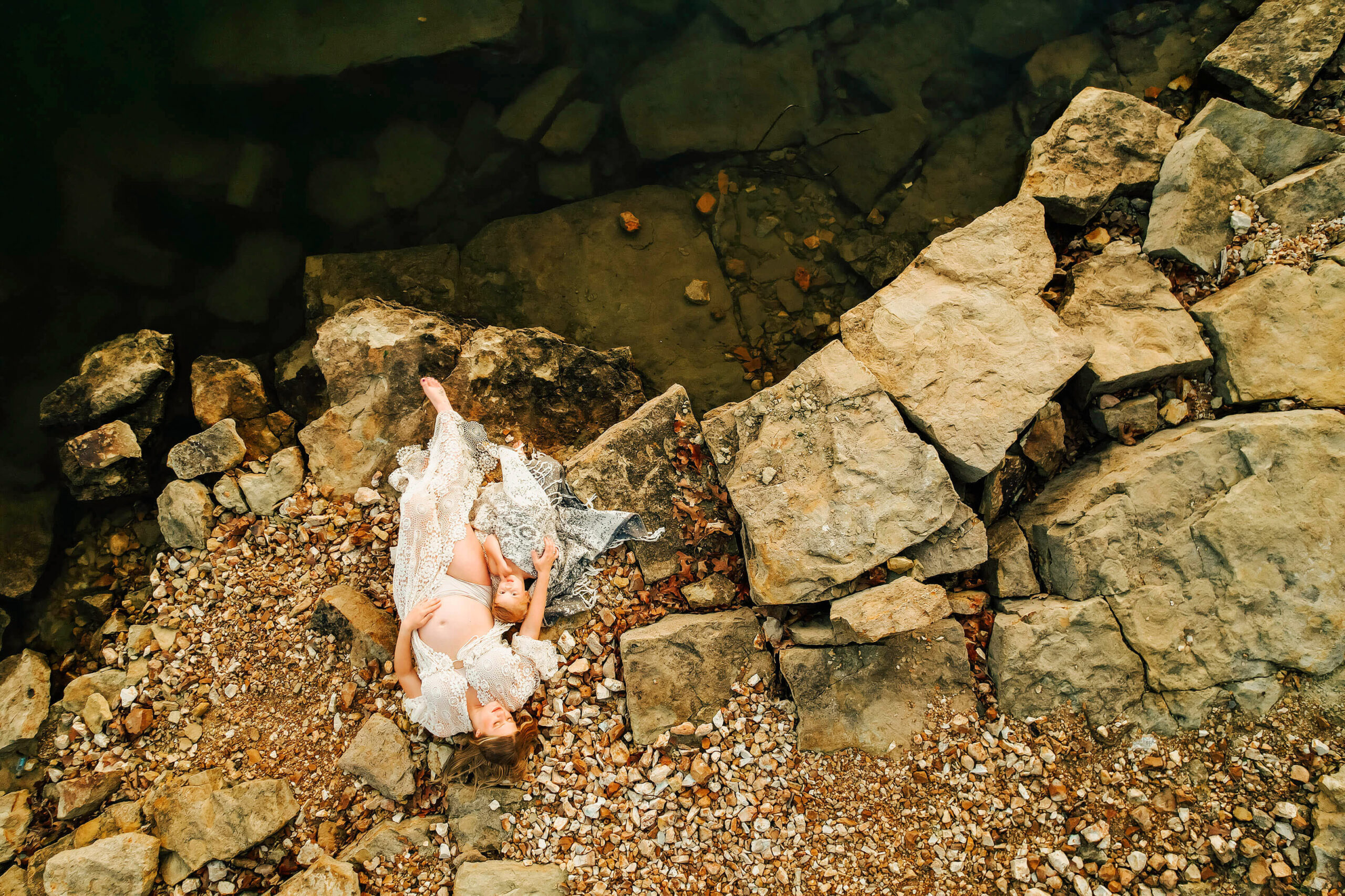 pregnant mom laying by the lake cuddling her toddler captured by The XO Photography