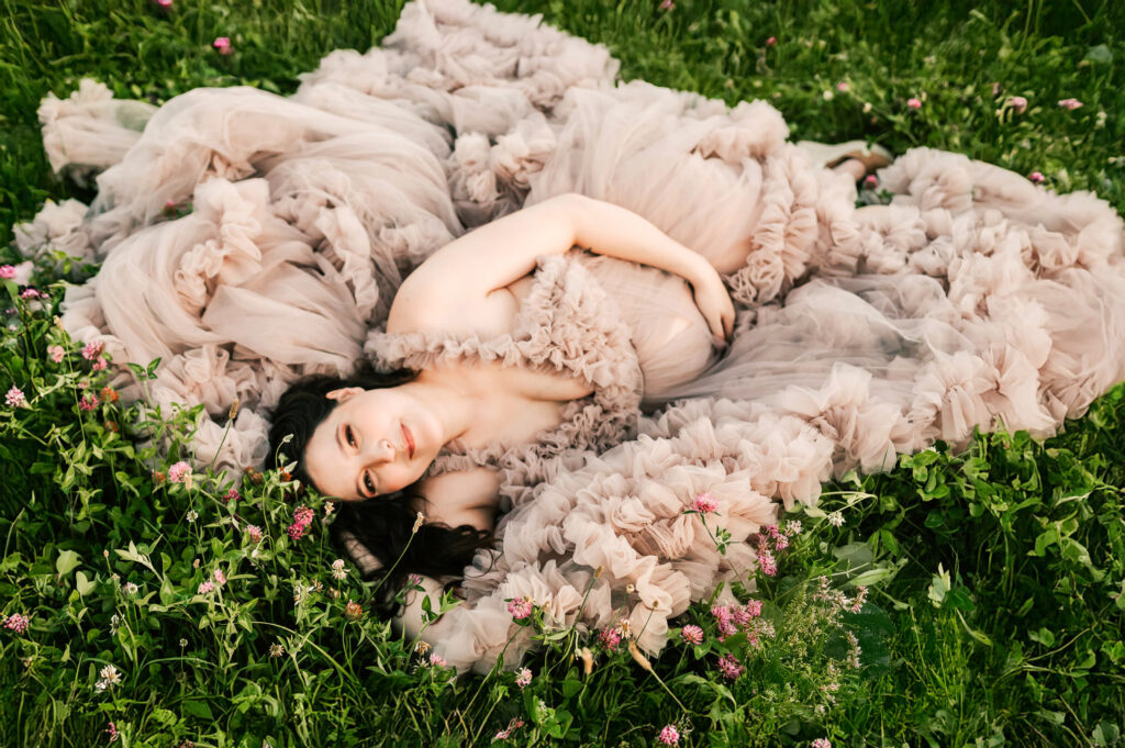 pregnant mom laying in the flowers captured by Springfield Mo maternity photographers The XO Photography