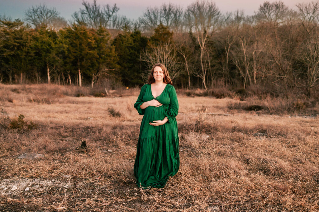 pregnant mom standing on walking trail in Springfield MO holding pregnant belly