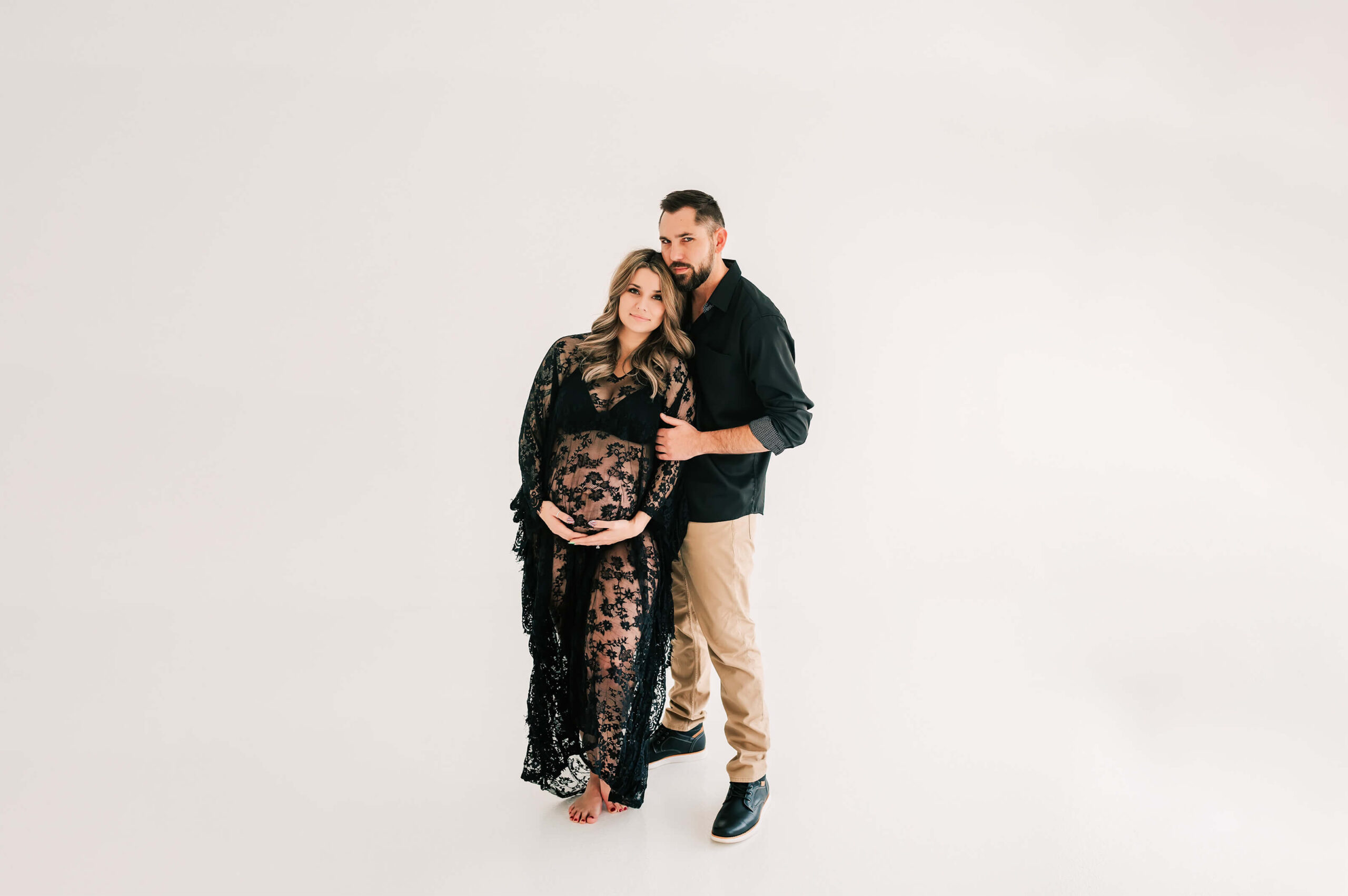 pregnant mom and husband in black cuddling in Springfield MO maternity photography studio