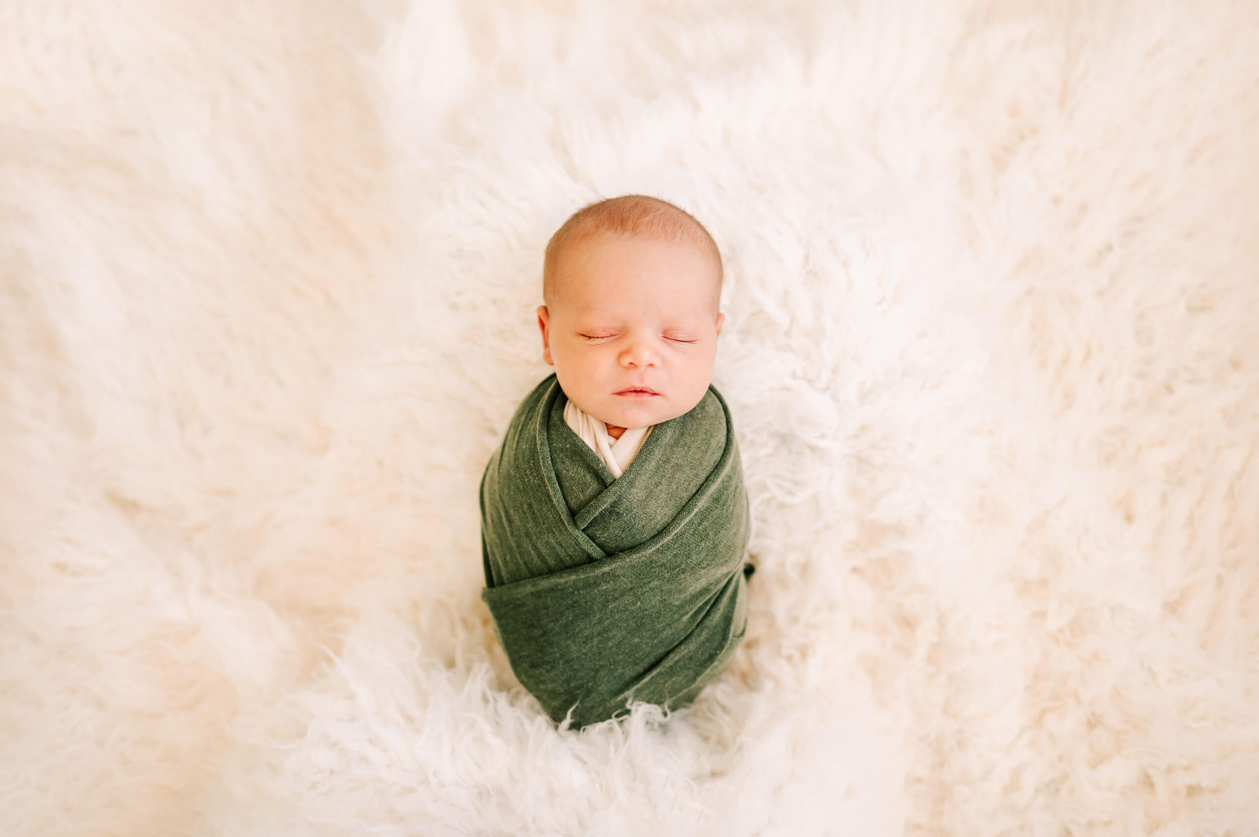 sleeping baby boy in green swaddle captured by Kansas City newborn photographer The XO Photography