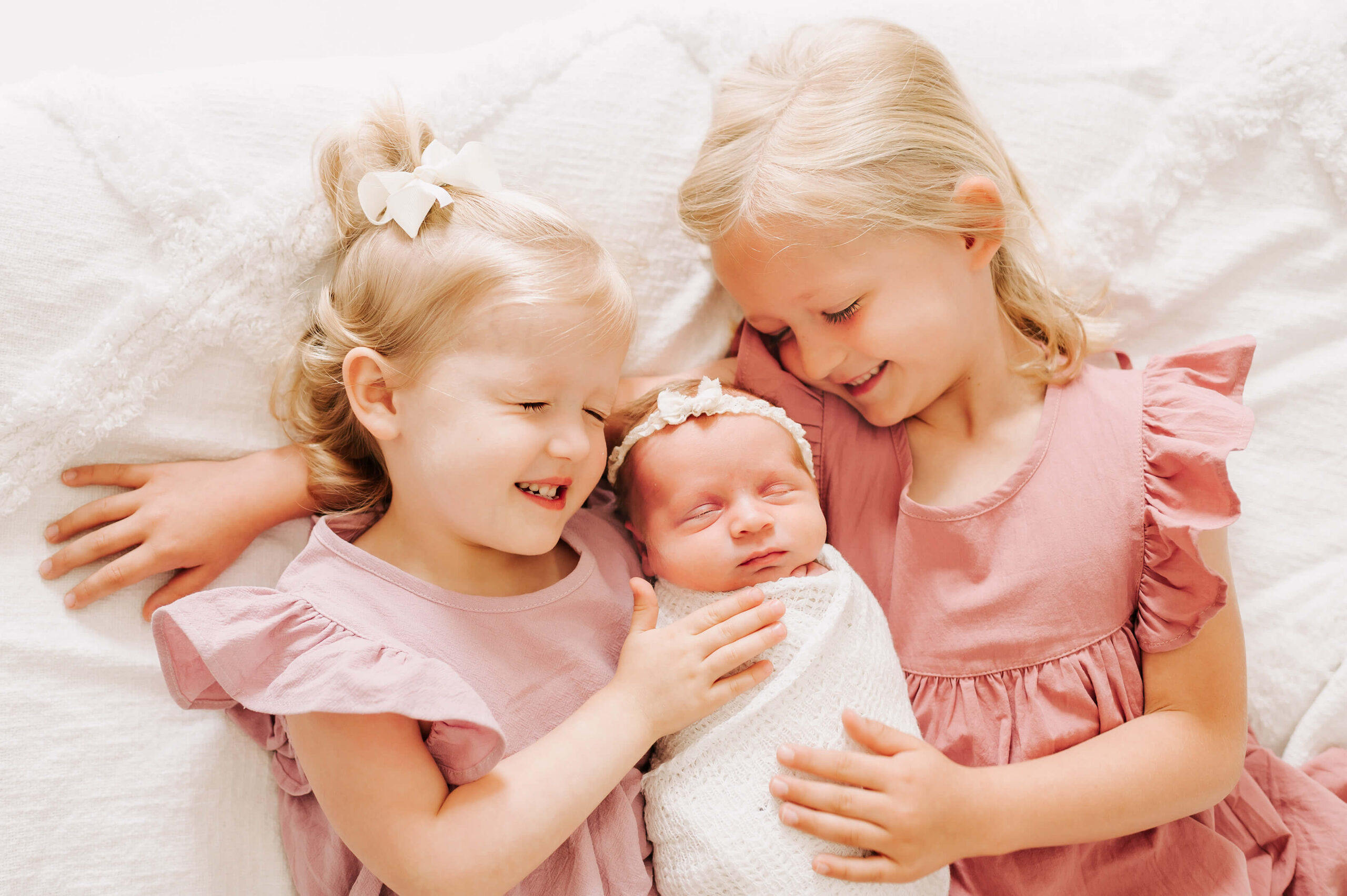 girls hugging baby sister captured by Springfield Mo newborn photographer The XO Photography