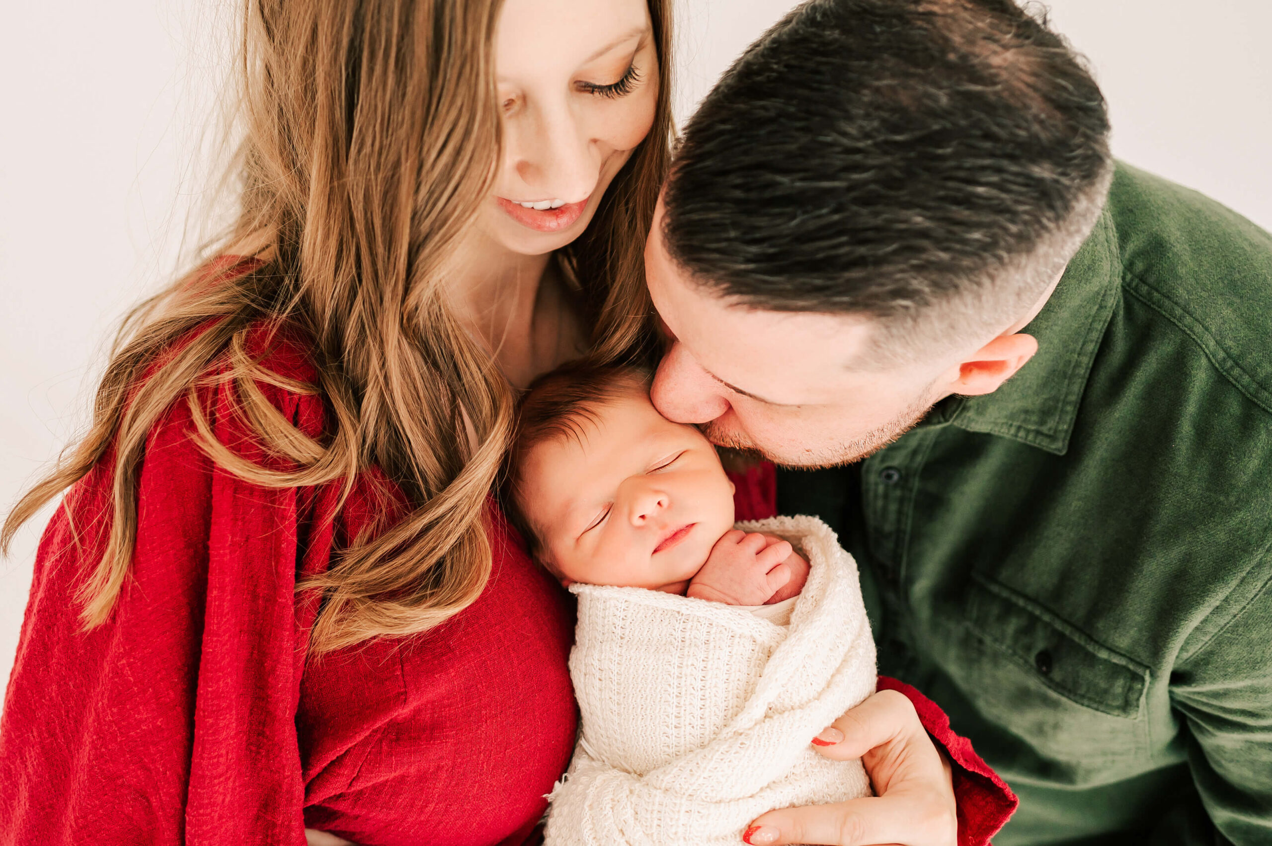 dad kissing sleeping newborn on moms chest captured by Springfield MO newborn photographer Jessica Kennedy of The XO Photography