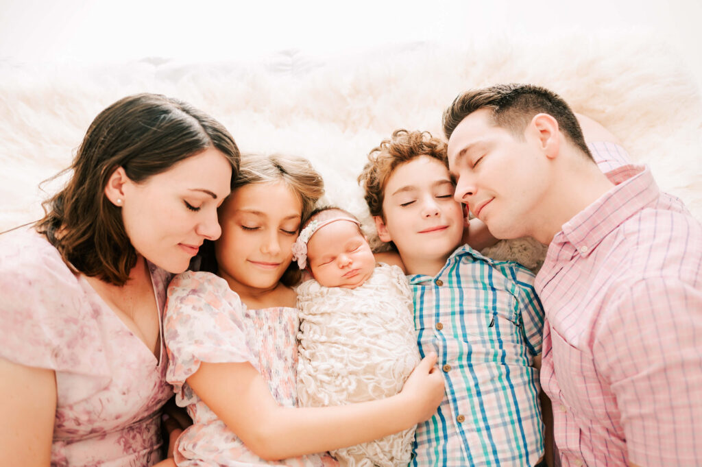 family cuddling in bed captured by Springfield MO newborn photographer Jessica Kennedy of The XO Photography