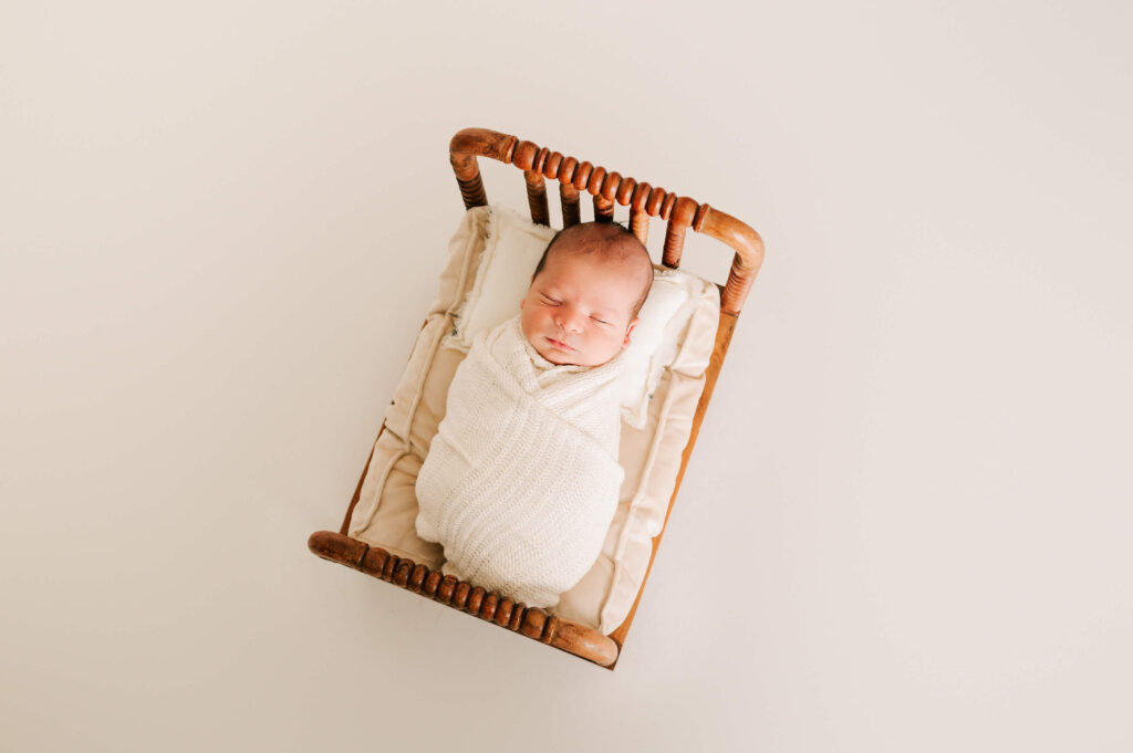 Springfield MO newborn photographer captures sleeping newborn in a small wooden crib in studio